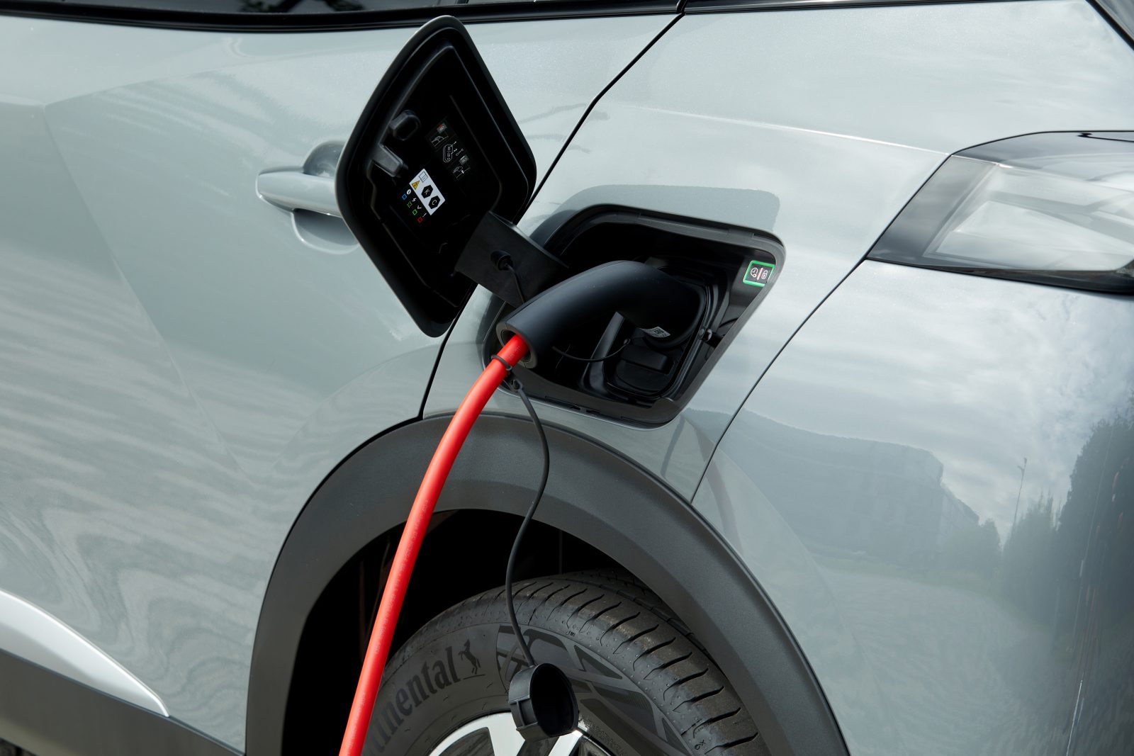 grey electric car plugged into charging cable