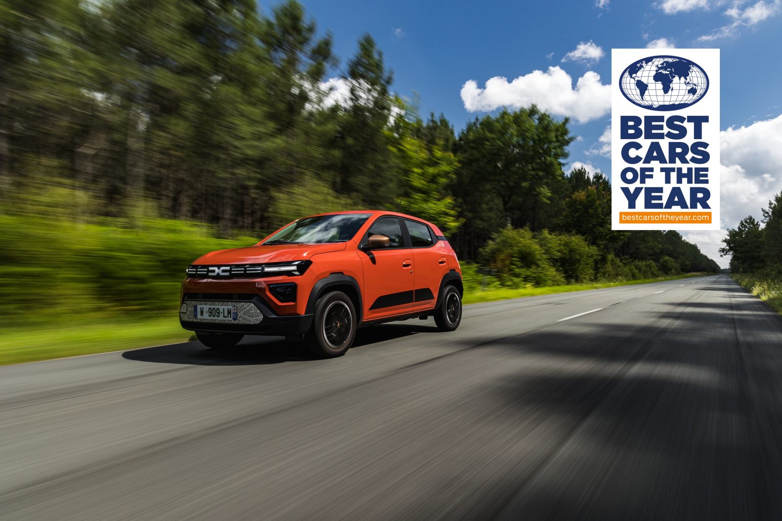 Dacia Spring - orange Electric Car driving on forest road 