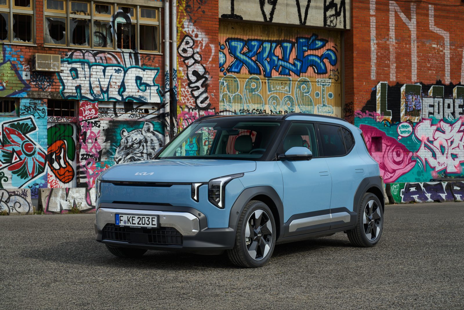 Kia EV 2 electric car in blue parked in front of graffiti wall