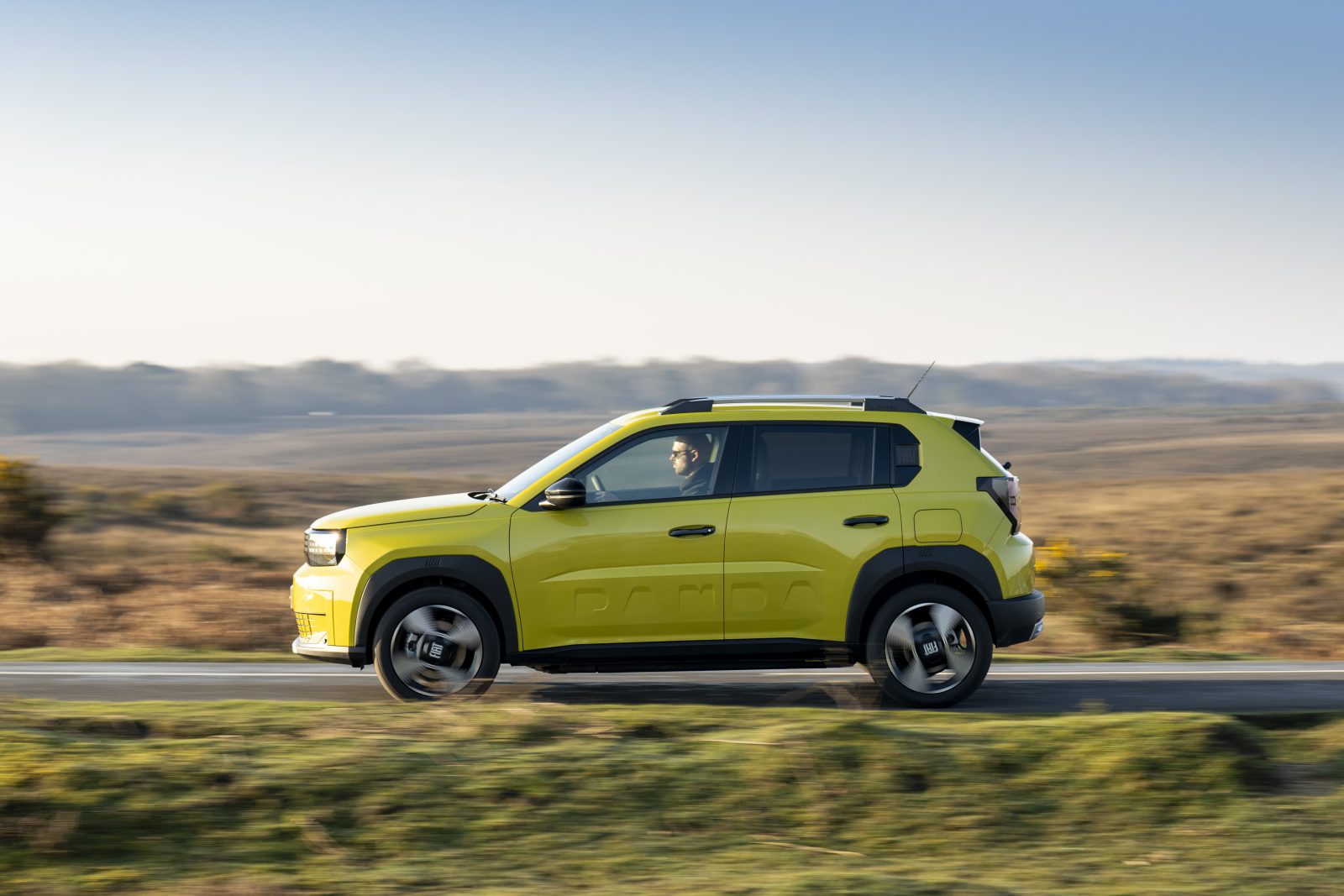 Fiat Grande Panda Electric in bright yellow driving in British countryside